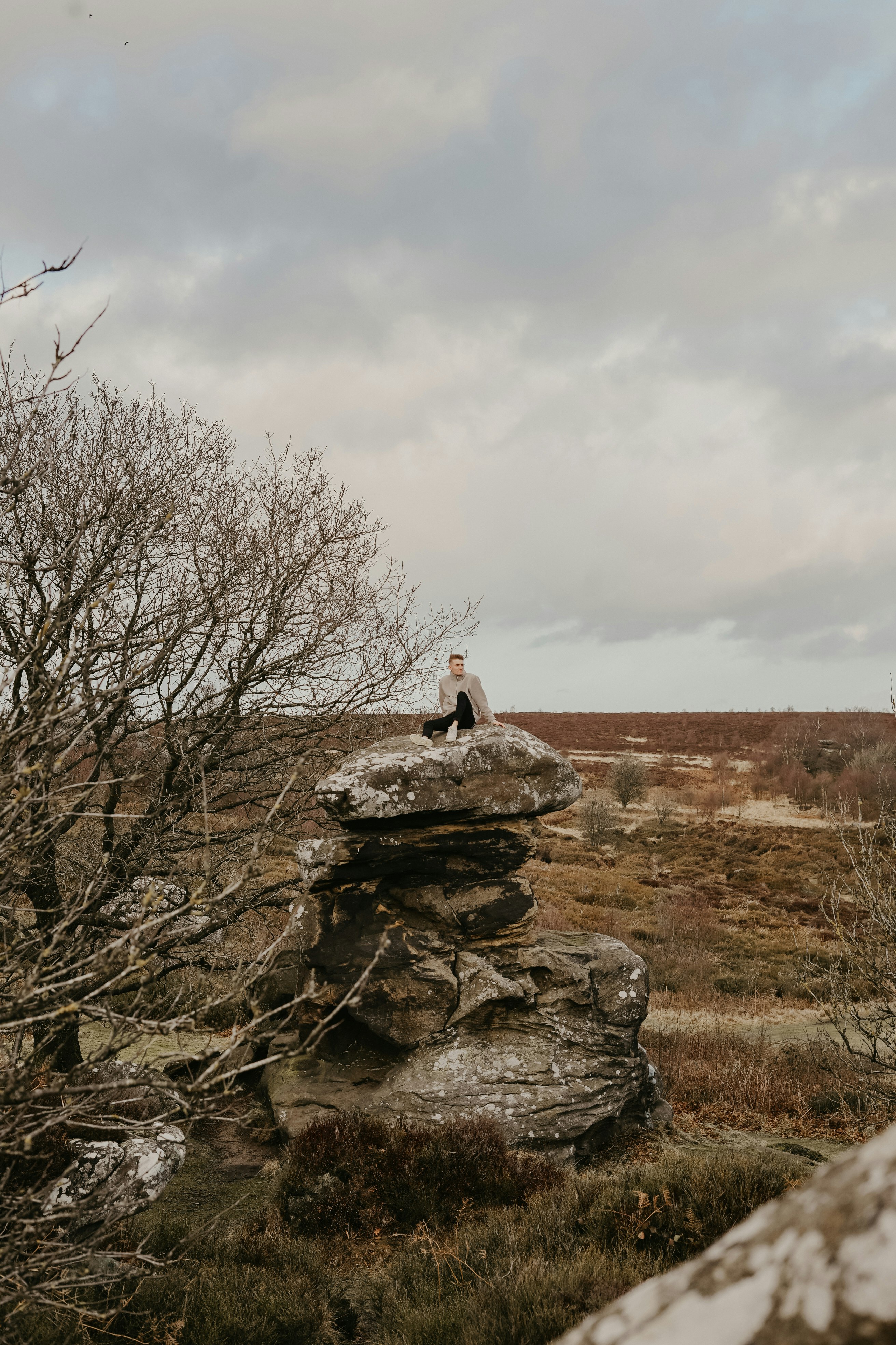 person sitting on piled rocks near trees during daytime